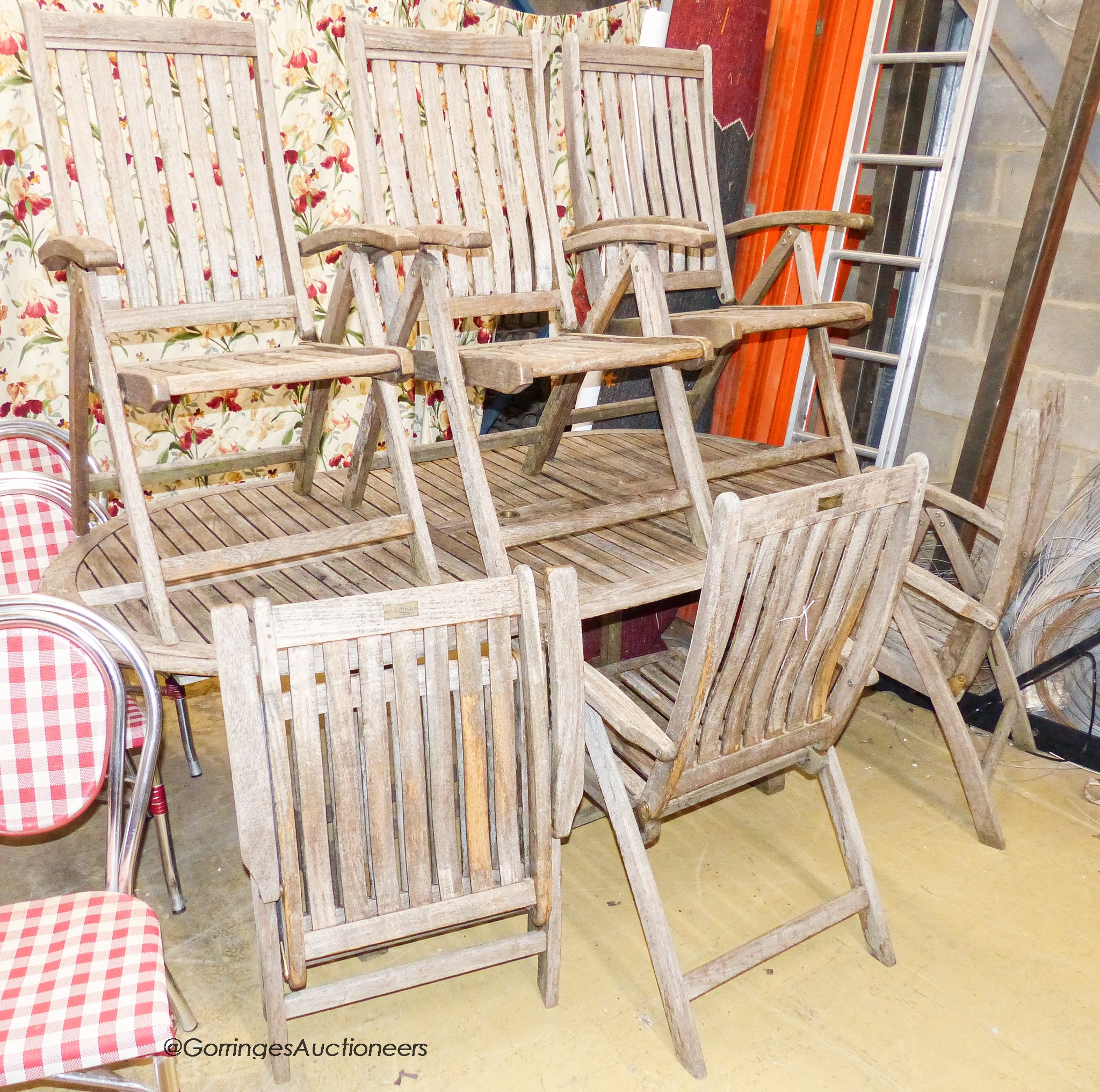 A weathered teak extending garden table, 204cm extended, length 108cm, height 76cm together with six weathered teak folding garden armchairs, stamped Harrogate collection